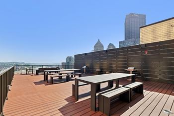 A rooftop patio with wooden flooring and furniture.